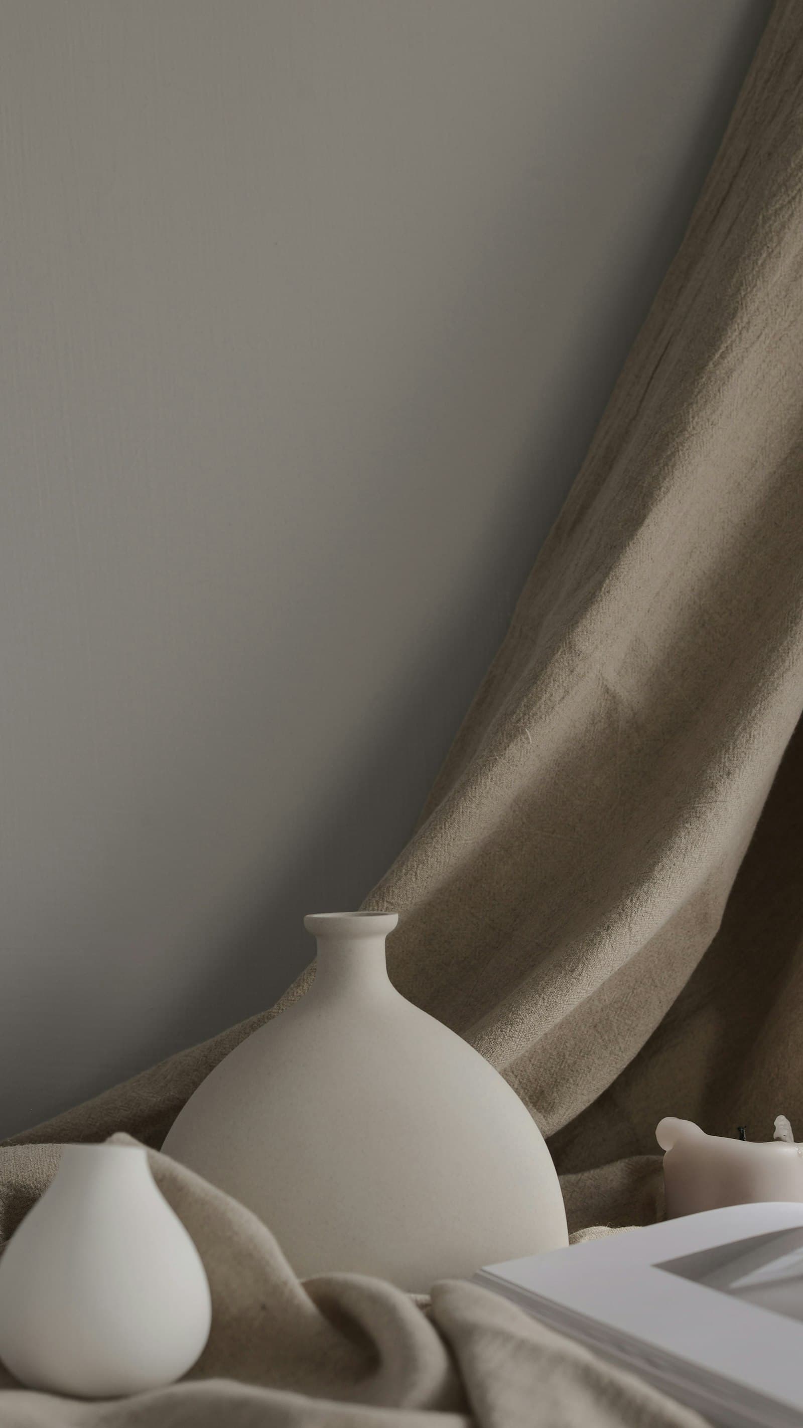 A pale stoneware bud vessel photographed against a fold of undyed linen.