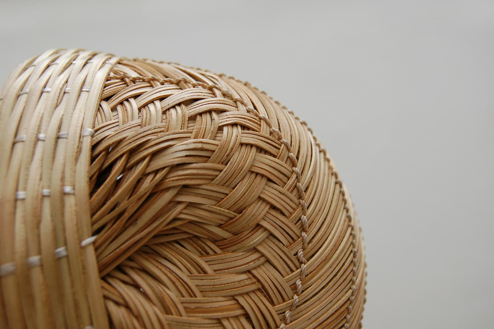 A round willow gathering basket, woven from pale rods, resting against a plain wall.